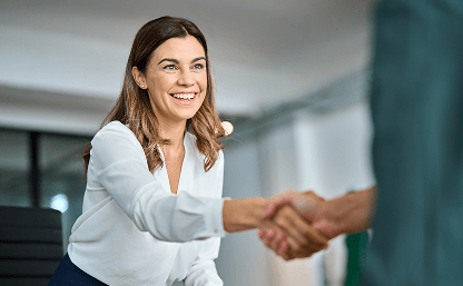 Mulher sorrindo cumprimentando alguém em um ambiente de escritório